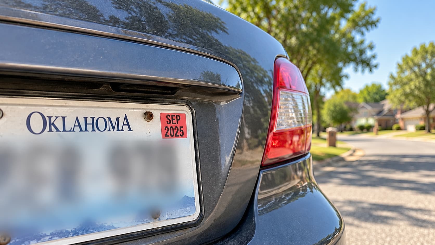 Close-up of an Oklahoma license plate with an expired September 2025 registration sticker on a parked car in Tulsa.